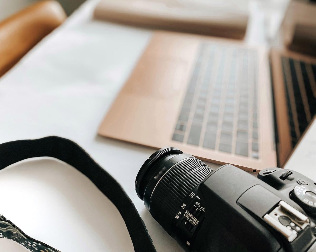 Appareil photo et ordinateur portable posés sur une table claire