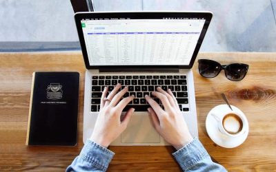 Une personne tapote sur un ordinateur portable sur une table en bois